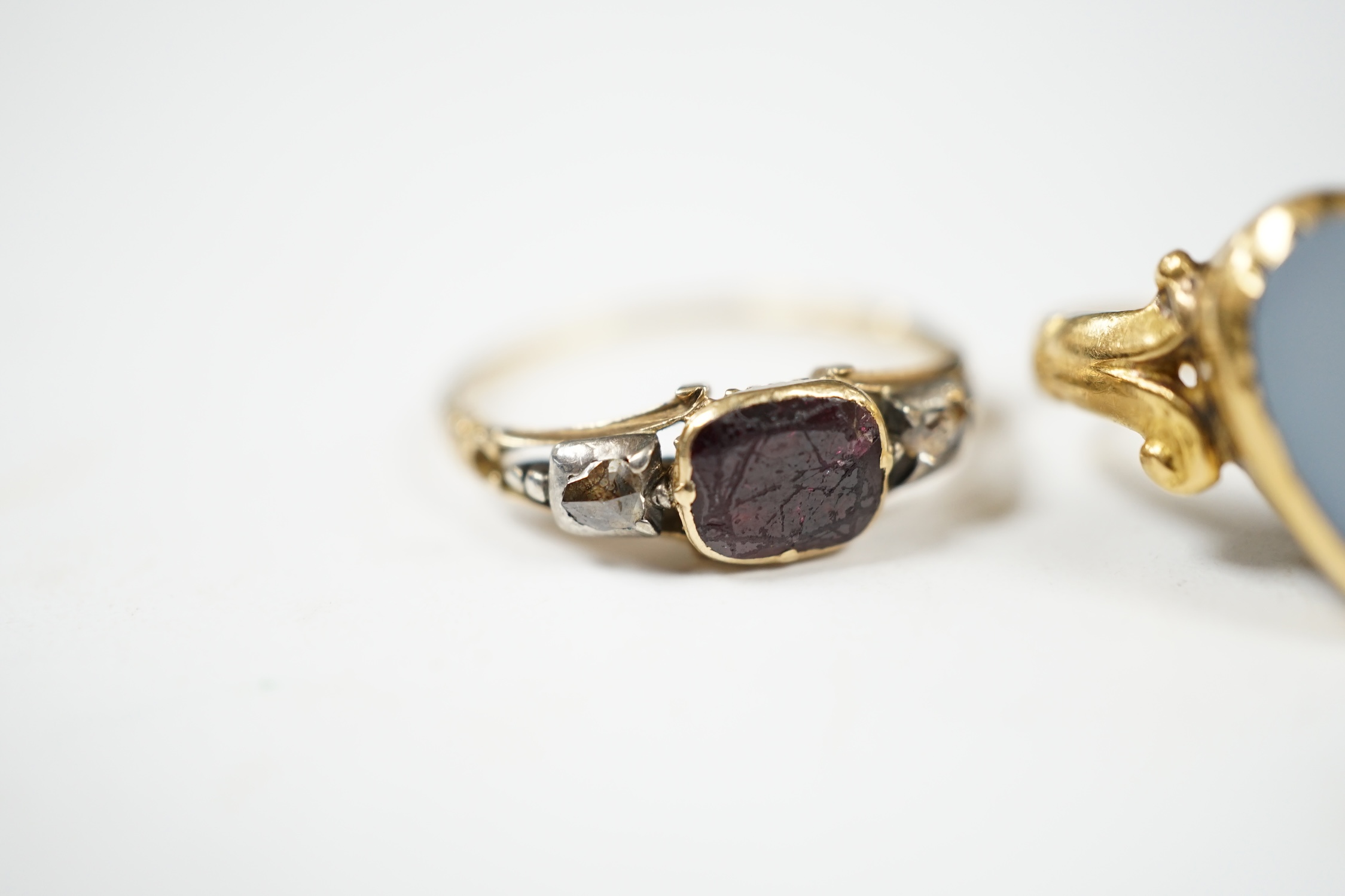 A Victorian yellow metal, garnet and rose cut diamond set three stone ring, size N/O, together with a later yellow metal and white chalcedony set heart shaped ring, gross weight 5.8 grams. Condition - poor